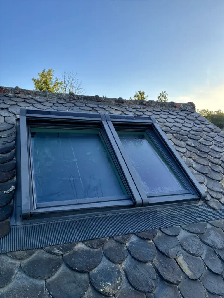 Installation finale d'une double verrière d'angle VELUX sur une toiture en ardoises.