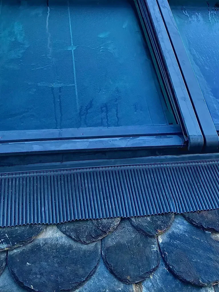 Zoom technique sur le raccord d'étanchéité d'un Velux et des ardoises.