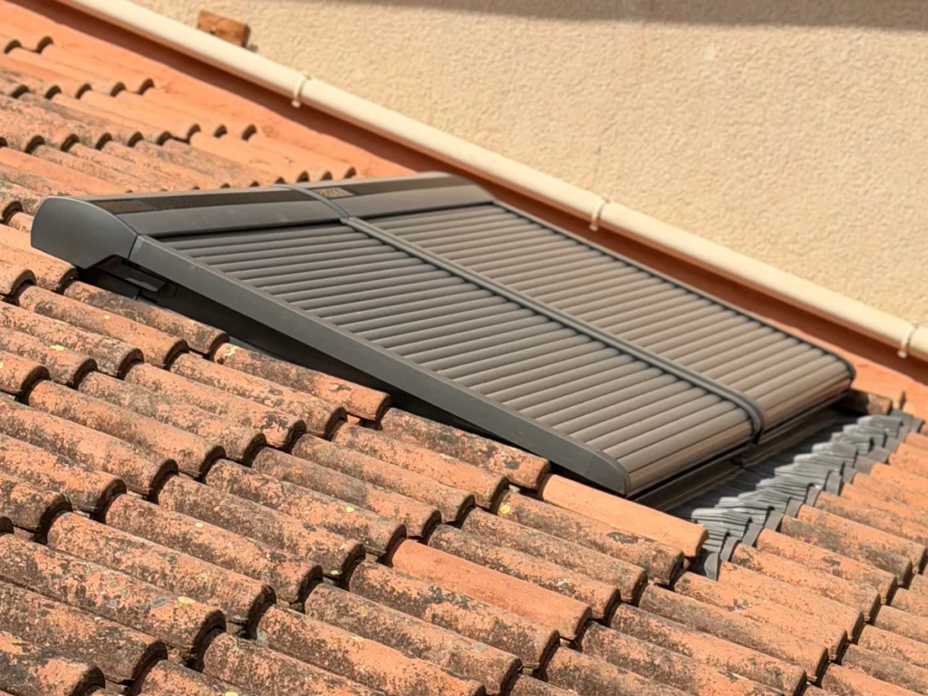Zoom sur les finitions d'étanchéité et les volets roulants fermés d'une verrière double VELUX sur toit en pente.